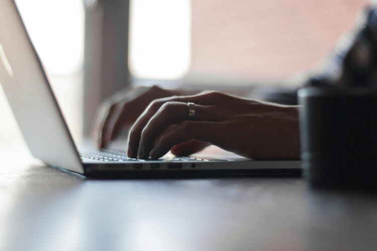 Person typing on a laptop to register a vacancy with HCRG Staffing